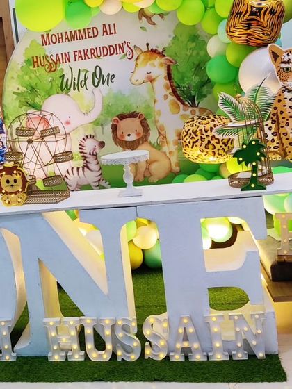 A "Wild One" jungle theme for a first birthday, featuring a large 'ONE' table, marquee letters, and cutouts of a leopard and zebra.