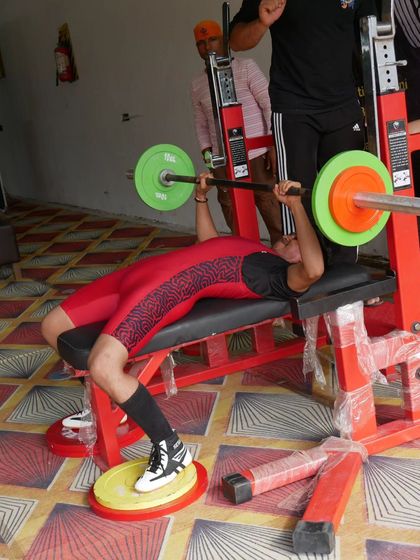 A fellow athlete competes in the bench press at the same district-level event. It's great to see the strength of the community.
