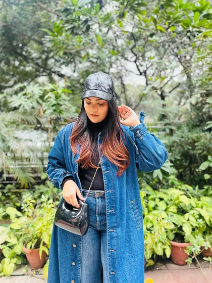 This small, black structured handbag is all about minimalist chic. Its glossy finish and clean lines make it a modern accessory that pairs perfectly with an edgy, double-denim look.