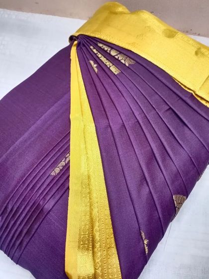 A deep purple saree with a bright yellow border, pleated and ready to be draped. My service makes wearing such bold, beautiful sarees completely effortless.