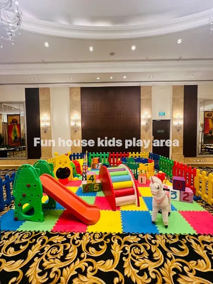 A wide shot of the indoor rainbow play area, featuring a slide, climber, rockers, and educational foam blocks.