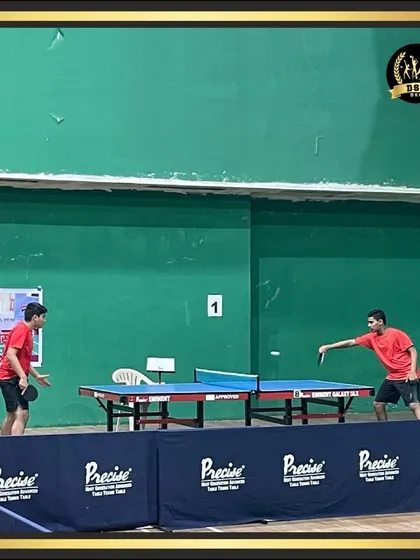 Two players practicing their table tennis skills. The setup includes court barriers, creating a professional environment for focused training sessions.