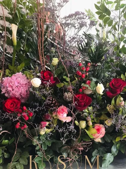 Christmas waves a magic wand over the world, making everything softer and more beautiful. This arrangement captures that feeling with a mix of red roses, pink hydrangeas, calla lilies, and festive pinecones.