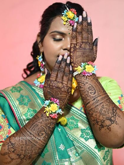 A portrait of a bride with her fully stained mehendi, complemented by floral jewelry. The dark henna looks stunning against her skin.