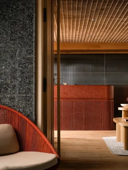A view into the Ulsoor workspace, where a monolithic reception desk in red terrazzo contrasts with the dark granite wall. The design balances raw, permanent materials with refined details.