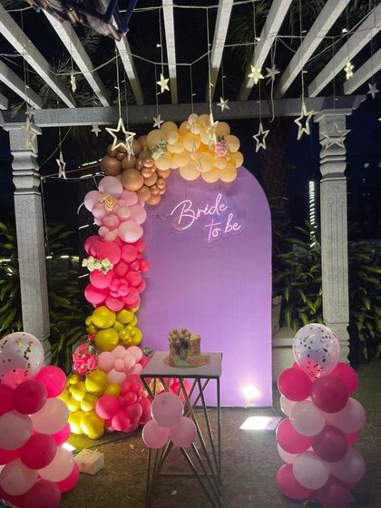 A wider shot of the outdoor 'Bride to be' party, showing the cake table and balloon columns.