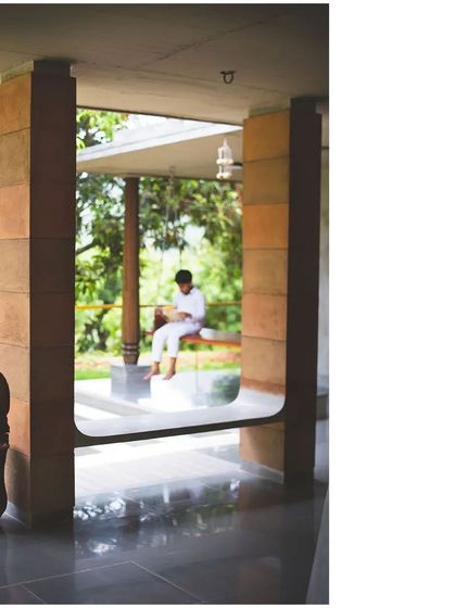 A detail of the 'Jagli' where the floor plane extends to form an integrated seat. This element, framed by earthy CSEB pillars, is a modern interpretation of a traditional 'katte', designed for informal seating and conversation.