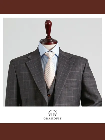 A closer look at the grey plaid three-piece, emphasizing the perfect harmony between the suit fabric, the light blue shirt, and the cream-colored tie.