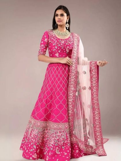 A full-length view of a model in a bright pink lehenga with silver embroidery. This outfit is perfect for a sangeet or mehendi ceremony.