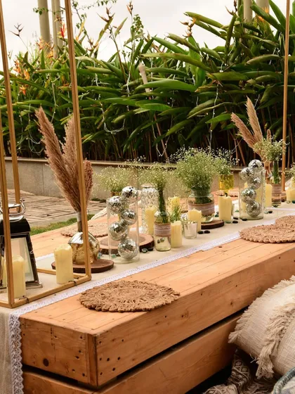 The full tablescape for our boho sundowner, featuring low wooden tables, an assortment of floor cushions, and a stunning overhead pampas grass installation.