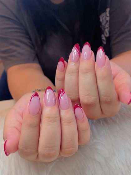 Abstract red French tips on almond nails, showing a creative and artistic take on the classic style.