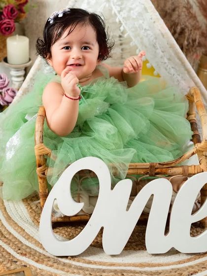 Celebrating one year with a big, happy smile. This little girl in her green dress is the picture of joy in this beautiful, rustic first birthday setup.