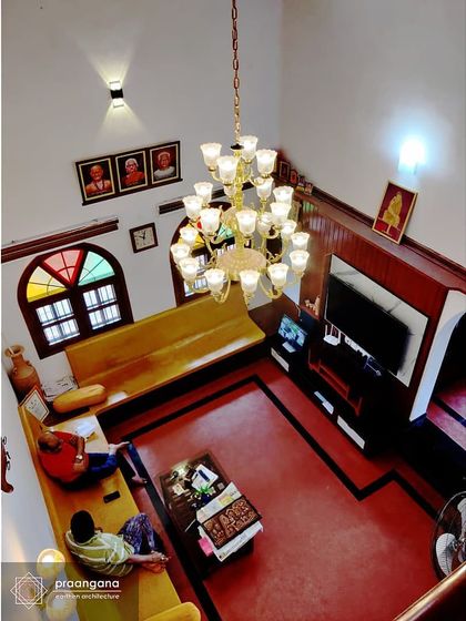 An overhead view of the living room in the Udupi house. The space is designed to be double-height, creating a sense of grandeur and openness, with traditional fixed seating along the walls.