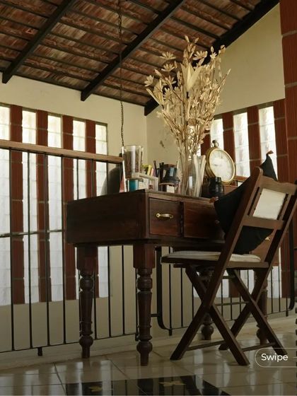A quiet workspace on a mezzanine level, overlooking the floor below. The use of traditional wooden furniture adds to the home's classic charm.