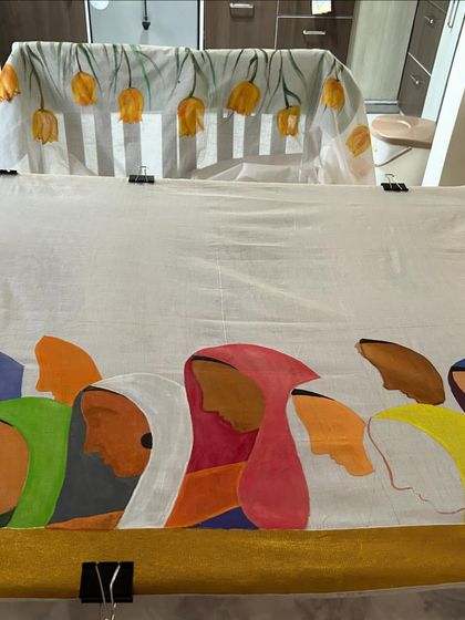 A work-in-progress shot of a hand-painted saree. On the top, you can see the floral border, and on the bottom, a panel depicting a group of women, a theme I often explore in my art.