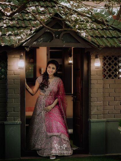 The bride-to-be posing in a doorway, her elegant lehenga and happy smile making for a beautiful portrait.
