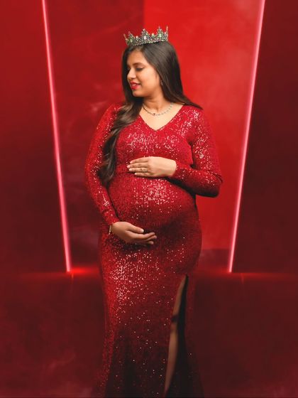 A regal portrait of an expecting mother wearing a crown with her red sequin gown, embodying the queen she is.