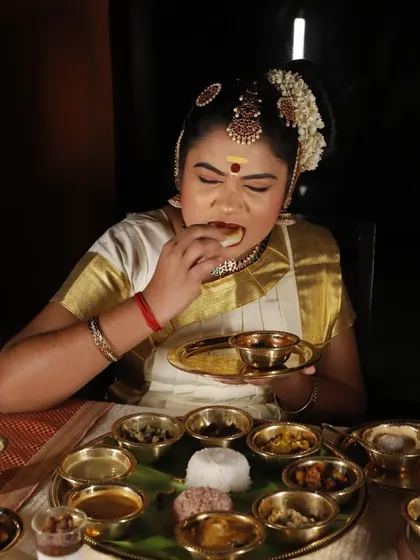 A Sadya is a performance of flavours, and this is the grand stage. A dancer, adorned in traditional attire, enjoys the feast, embodying the art and culture that is woven into every dish.
