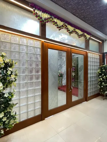The elegant entrance to the Devadiga banquet hall in Nerul. The glass block walls and simple floral arrangements provide a modern and clean look.