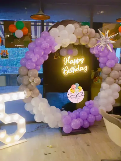 A sophisticated balloon ring in purple, grey, and white with a neon sign for a 5th birthday.