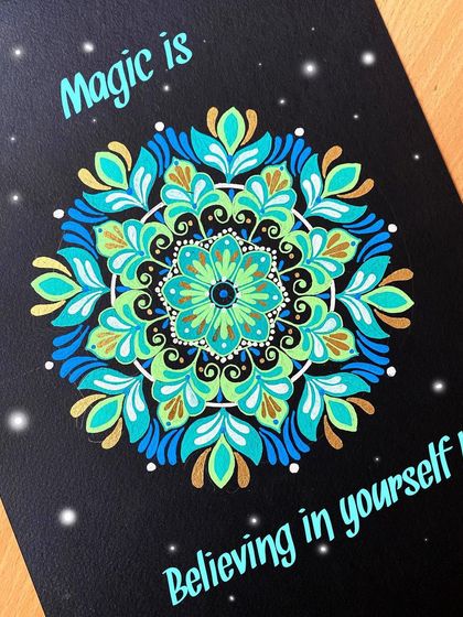 I love incorporating uplifting quotes into my art. This piece features the words "Magic is believing in yourself" around a vibrant blue, green, and gold mandala on black paper.