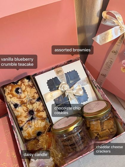 Here’s what goes inside one of my popular hamper sizes. You get a vanilla blueberry crumble teacake, assorted brownies, chocolate chip cookies, cheddar cheese crackers, and a daisy candle.
