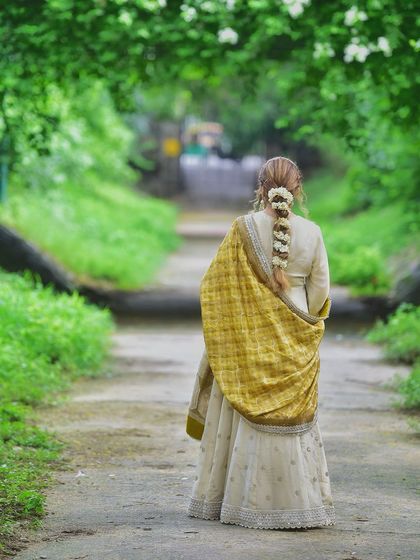 A beautiful back shot that highlights the elegant hairstyle with gajra and the rich texture of the dupatta. This pose creates a sense of mystery and grace.