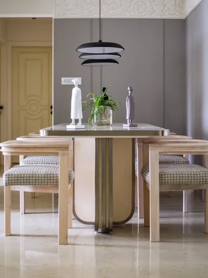 Calmness in chaos. The dining area of the 'YBJ Residence' is a serene space, with a marble-topped table, modern chairs, and delicate suspended lighting.
