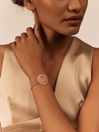 The Gulmohar Dusty Pink Bracelet is a dainty and feminine piece. Its teardrop-shaped pink stone, encircled with pearls, adds a soft touch of color to your wrist.