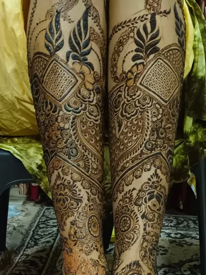 This design shows full leg mehendi, extending up from the feet. The patterns are dense and match the bridal hands.