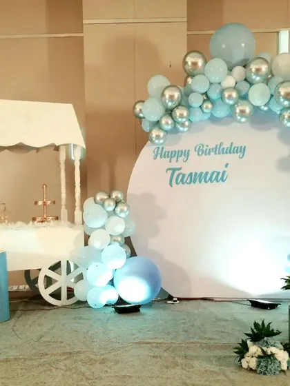 For a modern and elegant birthday, I created this pastel blue and silver chrome setup for Tasmai. The design includes a clean, circular white backdrop for personalized messaging, a stylish dessert cart, and a sophisticated balloon half-arch.