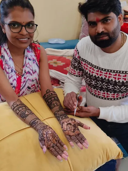 Me with a happy client, showing her freshly completed bridal mehandi featuring intricate portraits.