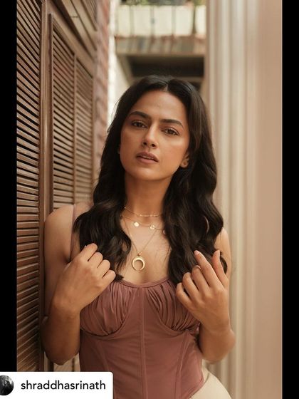 This image showcases the delicate details of the layered necklaces and the texture of the mauve top, key elements of this soft glam styling.