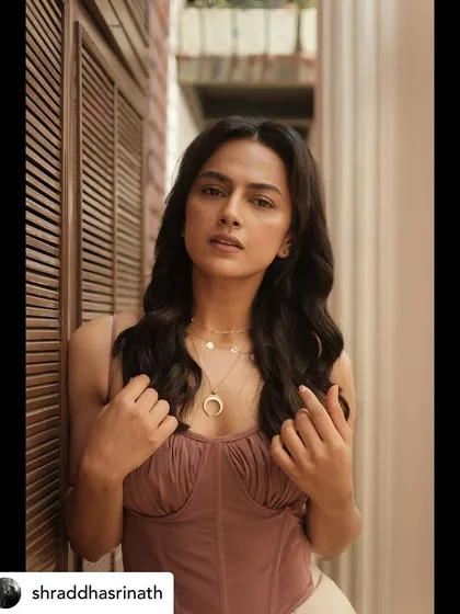 This image showcases the delicate details of the layered necklaces and the texture of the mauve top, key elements of this soft glam styling.