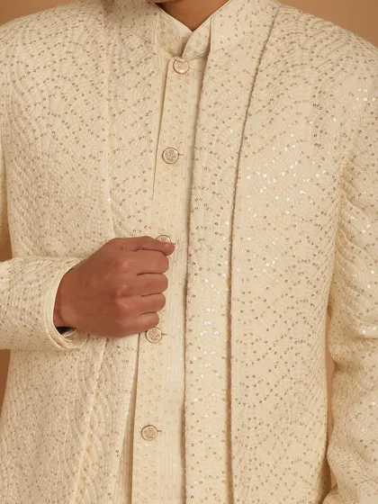 A close-up of the fabric of an ivory Indo-Western jacket, showing the subtle, shimmering embroidery that catches the light beautifully. It's all in the details.
