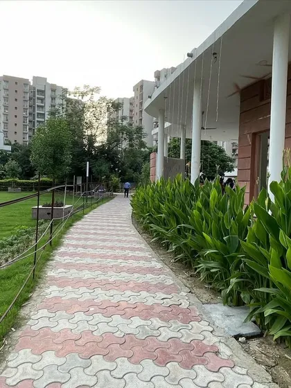 A winding walkway made of red and grey interlocking tiles meanders through this community park. I lined the path with lush canna lily plants, adding greenery and structure next to the building.