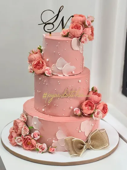 A three-tiered blush pink cake adorned with delicate florals, pearls, and a beautiful velvet bow. This design was crafted to make a special engagement day feel both grand and magical.