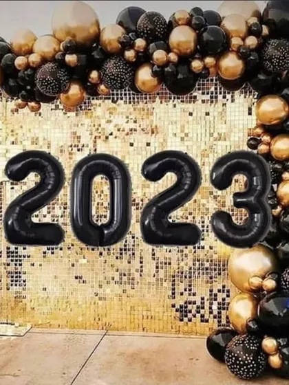 Ring in the New Year with a glamorous party. This setup for a 2023 celebration features a stunning gold shimmer wall with black and gold balloons, creating a sophisticated backdrop for your countdown.