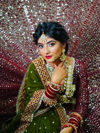 A royal bridal look featuring a green velvet shawl. The makeup is bold and classic, with a timeless red lip.