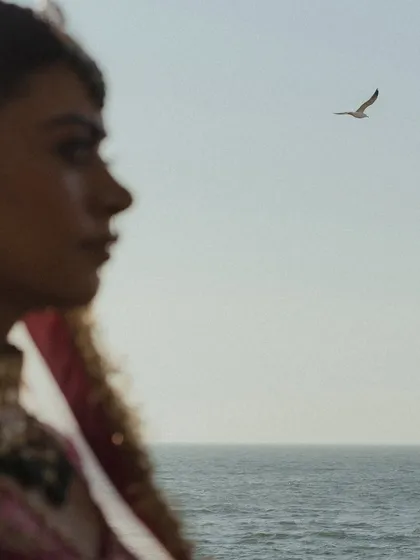 An artistic, out-of-focus shot of the bride's profile against the sea, with a bird flying in the distance. This poetic image captures the feeling of a seaside wedding in Mumbai.