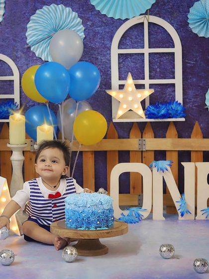 This little sailor is all set for his blue-themed cake smash! The nautical-inspired outfit and beautiful blue ombre cake make this first birthday session so special.
