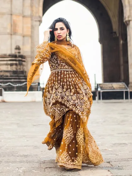 A full-length shot of a bride in a gorgeous mustard-colored gown, walking with confidence. This portrait captures her fearless beauty against a historic backdrop.