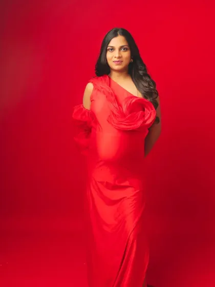 A full-length portrait in our vibrant red gown with floral shoulder details, exuding confidence and modern elegance.