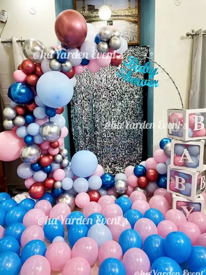 A room filled with pink and blue balloons for a gender reveal party. The silver sequin backdrop and 'BABY' blocks add to the excitement.