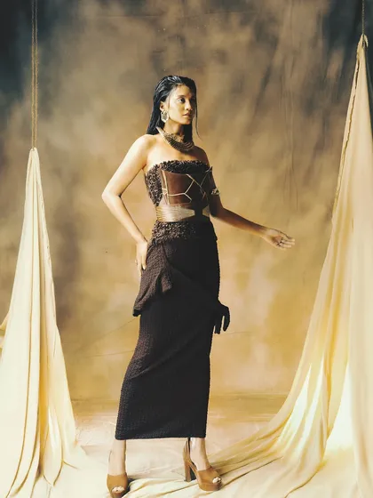 The full look, where the bronzed skin and subtle makeup perfectly complement the textured, earth-toned outfit.