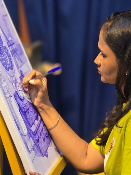 A close-up view of the artistic process. This image captures a student's focused expression as she adds fine details to her ballpoint pen still life on canvas.