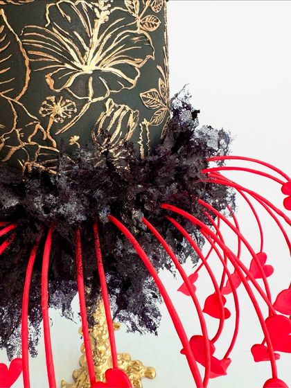 A close-up of the "Eclipsed Romance" cake, showing the texture of the black sugar lace and the intricate gold painting.