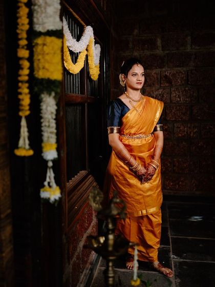 A dramatic shot of the bride in her Madisar. The lighting highlights the beautiful drape of the saree and her classic, elegant makeup.