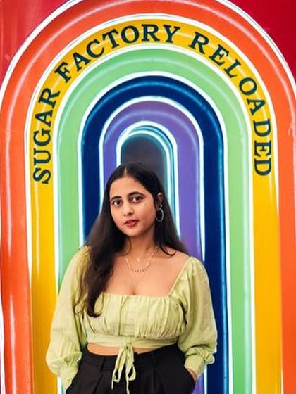 A guest posing at the colorful, illuminated entrance of Sugar Factory.