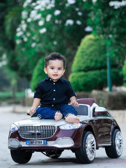 This baby is sitting on the hood of his car, looking cool and ready for a ride.